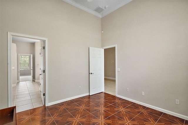 unfurnished bedroom with crown molding, a high ceiling, tile patterned floors, and baseboards