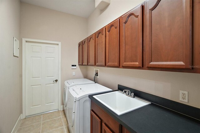 washroom with cabinet space, light tile patterned floors, baseboards, washer and clothes dryer, and a sink