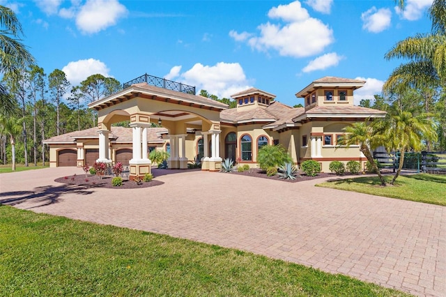 view of front of property with a balcony, stucco siding, a front lawn, a garage, and decorative driveway