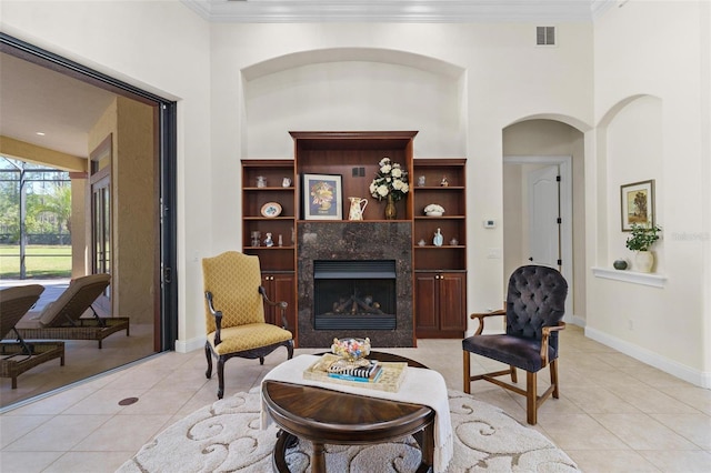 living room featuring light tile patterned floors, baseboards, visible vents, a fireplace, and ornamental molding