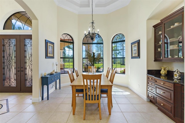 dining space with french doors, light tile patterned flooring, crown molding, a chandelier, and a towering ceiling