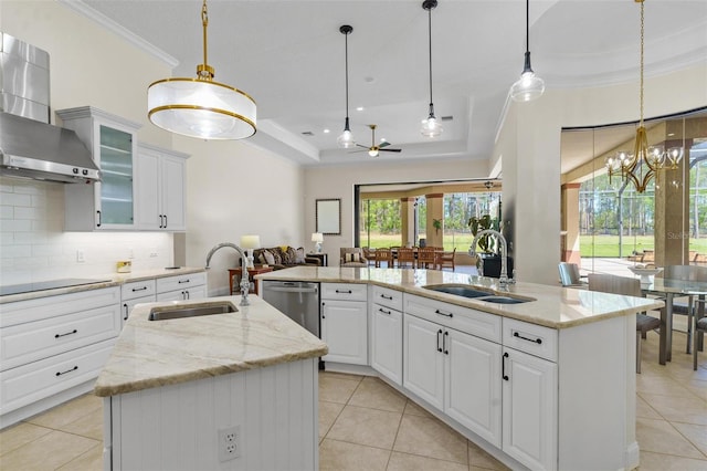 kitchen featuring stainless steel dishwasher, wall chimney exhaust hood, a center island with sink, and a sink