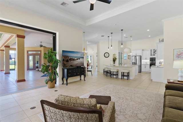 living area featuring light tile patterned floors, visible vents, and crown molding