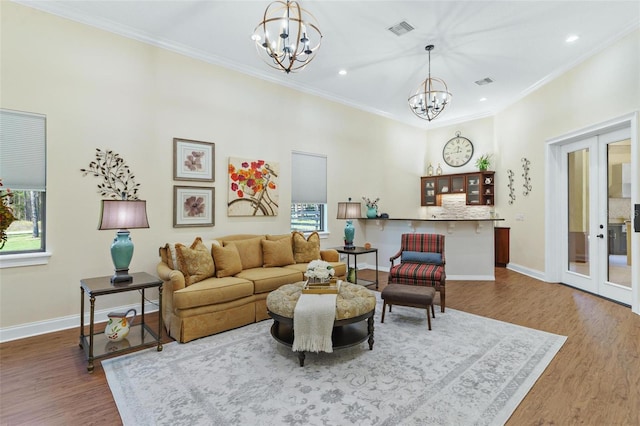 living room featuring a notable chandelier, visible vents, french doors, and ornamental molding