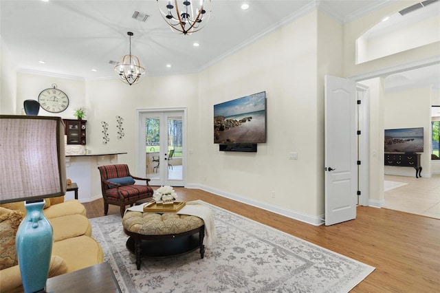 living area featuring visible vents, ornamental molding, wood finished floors, french doors, and a chandelier