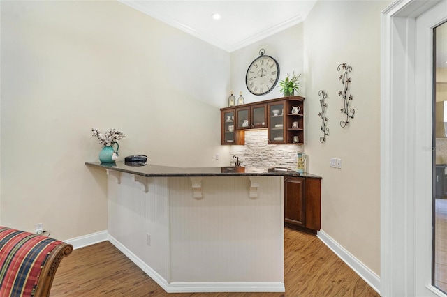 bar with light wood-type flooring, baseboards, and tasteful backsplash