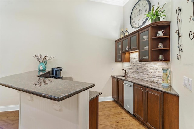 bar featuring baseboards, a sink, crown molding, light wood-type flooring, and backsplash