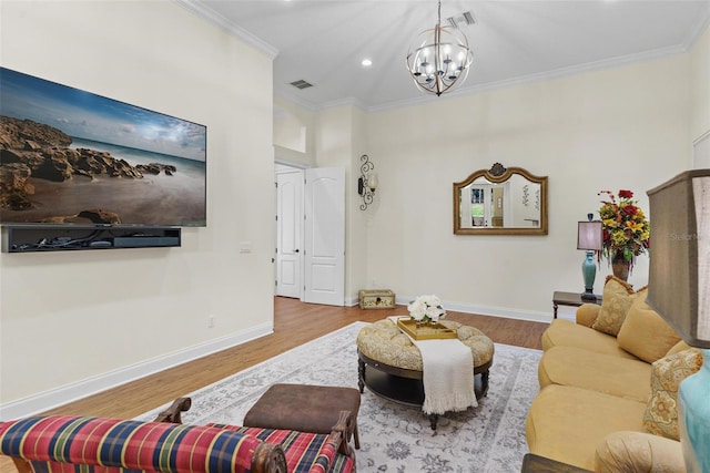 living area with visible vents, ornamental molding, wood finished floors, baseboards, and a chandelier