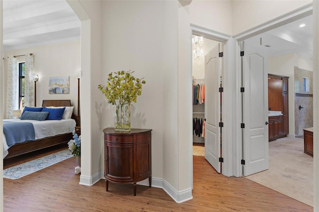 hall with baseboards, arched walkways, and light wood finished floors