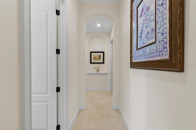 corridor featuring light tile patterned floors and baseboards