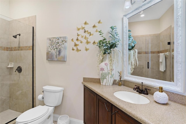 bathroom with toilet, a stall shower, vanity, and baseboards