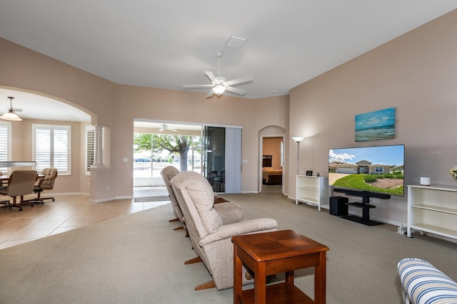 tiled living area featuring baseboards, arched walkways, and carpet flooring