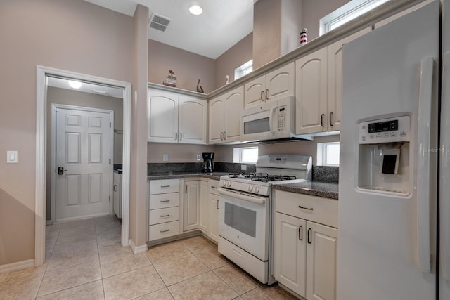 kitchen featuring light tile patterned floors, visible vents, a healthy amount of sunlight, white appliances, and baseboards