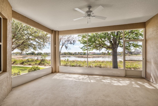 unfurnished sunroom with a water view, ceiling fan, and a wealth of natural light