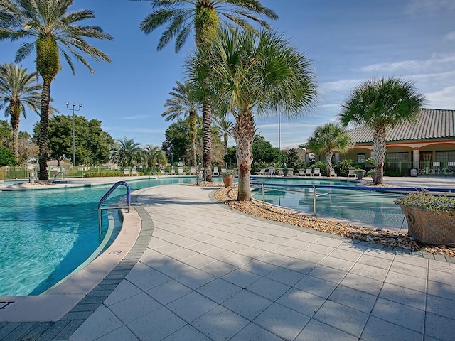 pool with a patio area and fence