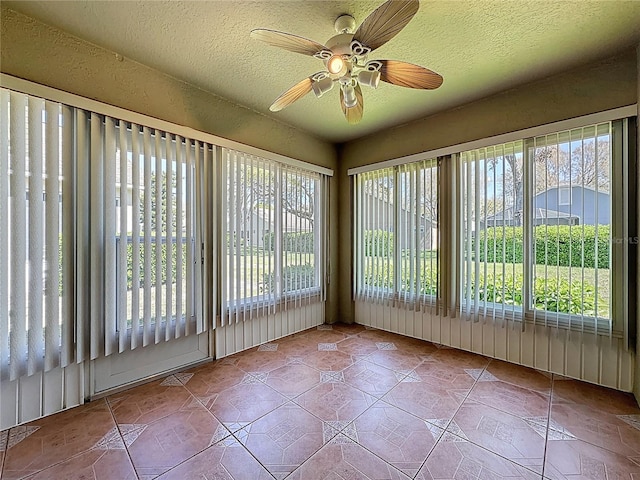 unfurnished sunroom with a ceiling fan and plenty of natural light