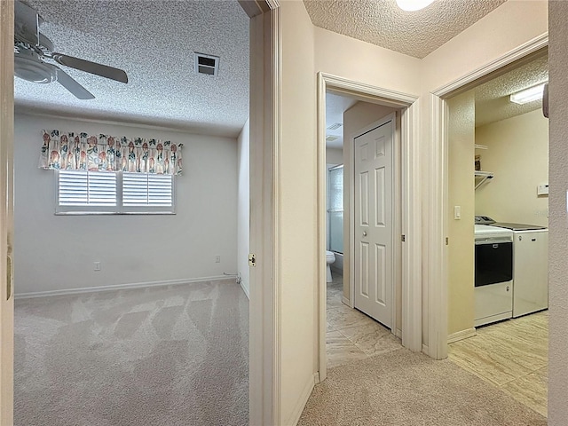 hall with baseboards, light colored carpet, visible vents, and a textured ceiling