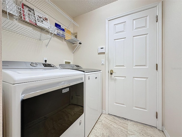 laundry room with laundry area, baseboards, a textured ceiling, and washing machine and clothes dryer