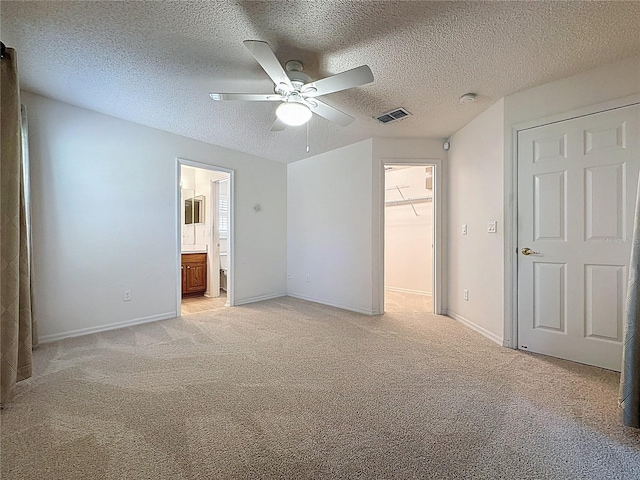 unfurnished bedroom with light carpet, baseboards, visible vents, a walk in closet, and a closet