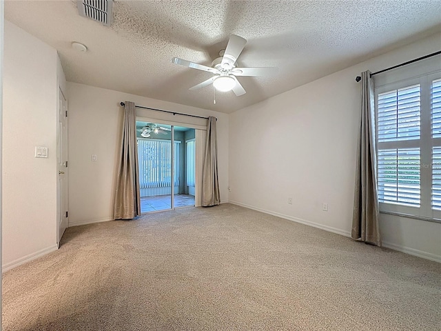 unfurnished room featuring a textured ceiling, light carpet, visible vents, baseboards, and a ceiling fan