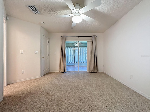 empty room featuring a textured ceiling, a ceiling fan, visible vents, and light colored carpet