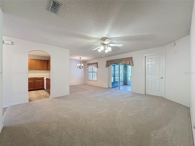 unfurnished living room with visible vents, light carpet, a textured ceiling, baseboards, and ceiling fan with notable chandelier