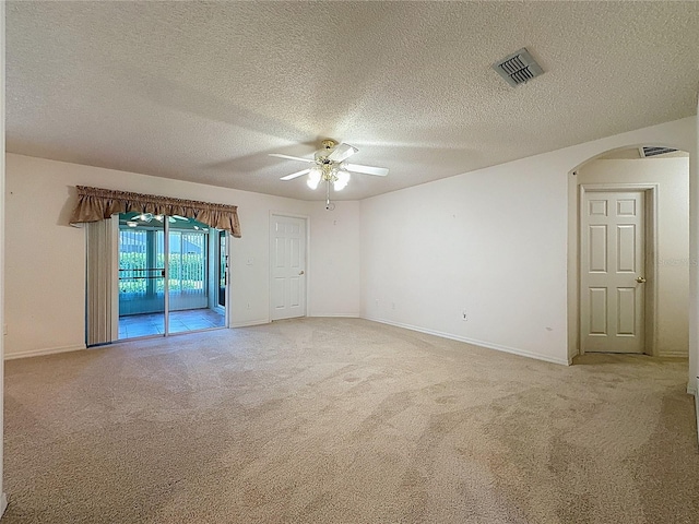 spare room with light carpet, arched walkways, visible vents, and a ceiling fan