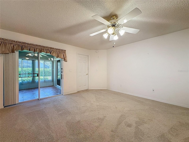 spare room featuring light carpet, ceiling fan, a textured ceiling, and baseboards