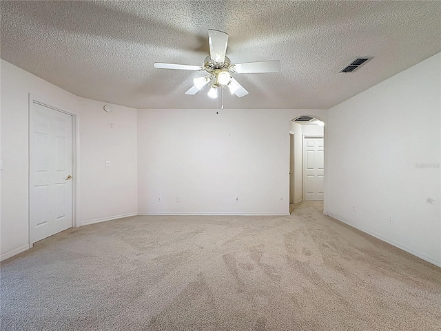 empty room featuring arched walkways, visible vents, light carpet, ceiling fan, and a textured ceiling