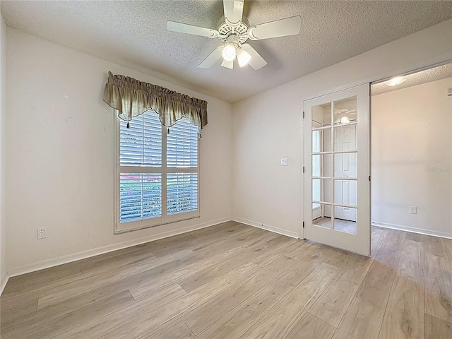 unfurnished room with light wood-style floors, ceiling fan, baseboards, and a textured ceiling