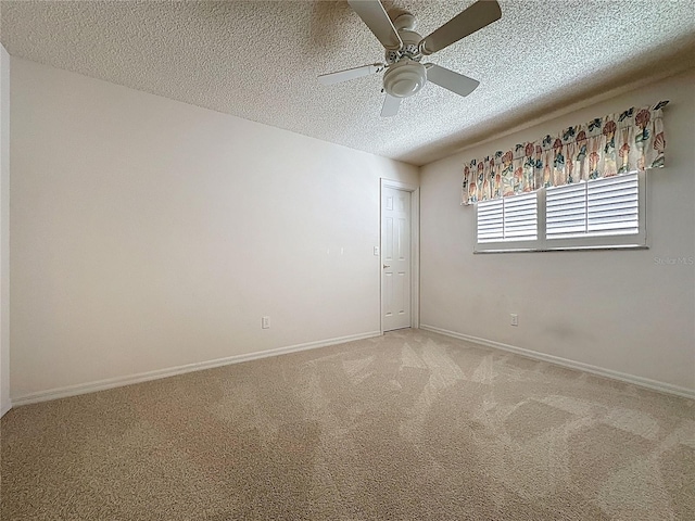 spare room with ceiling fan, baseboards, a textured ceiling, and light colored carpet