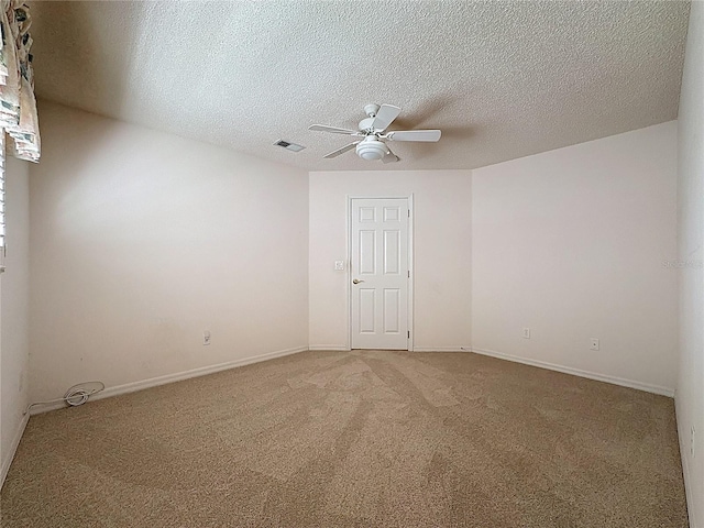 carpeted spare room featuring visible vents, ceiling fan, a textured ceiling, and baseboards