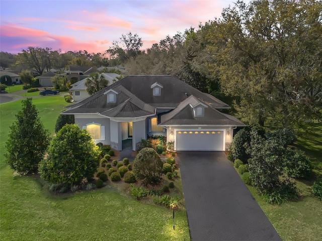 craftsman house with decorative driveway, an attached garage, and a lawn