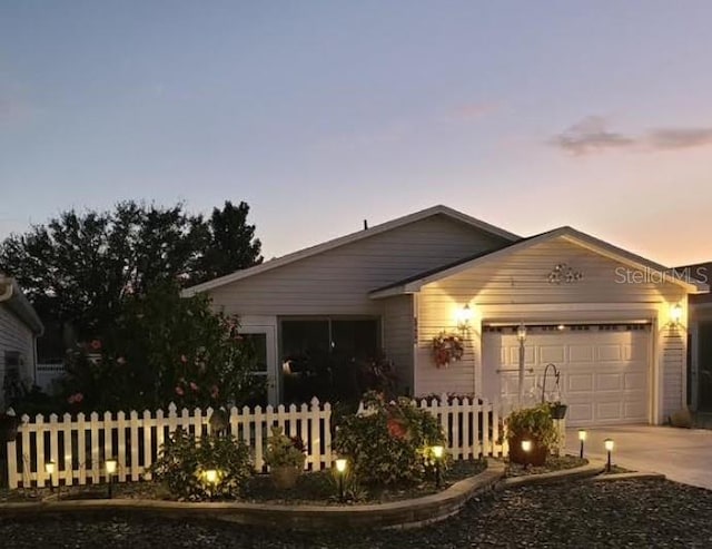 view of front of house with concrete driveway, fence, and an attached garage