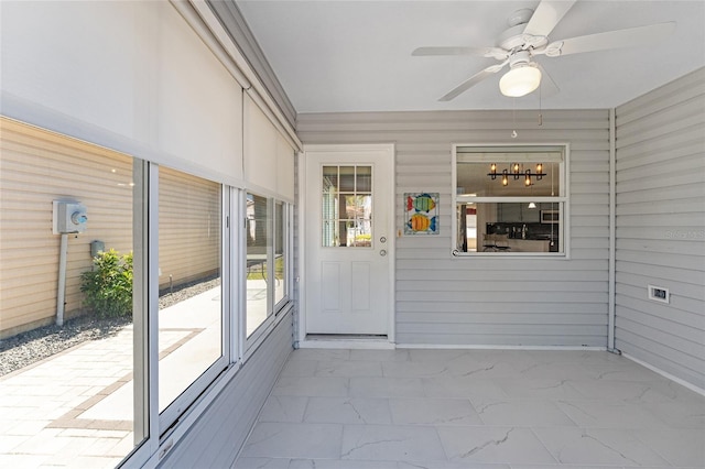 unfurnished sunroom featuring a ceiling fan