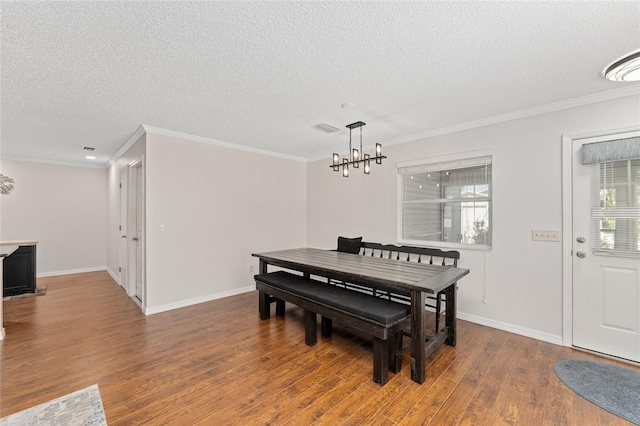 dining area featuring a chandelier, wood finished floors, visible vents, baseboards, and crown molding