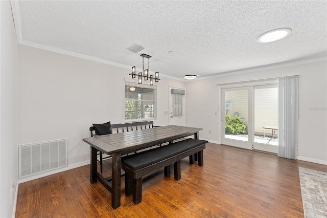 dining space featuring a textured ceiling, visible vents, wood finished floors, and ornamental molding