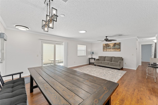 dining room featuring baseboards, crown molding, a ceiling fan, and wood finished floors