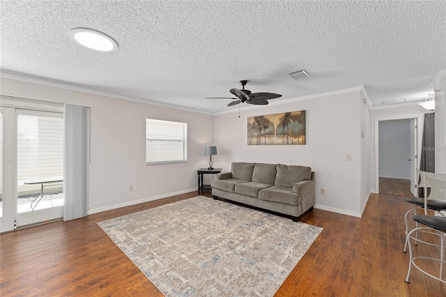 living area with ornamental molding, visible vents, dark wood finished floors, and a ceiling fan