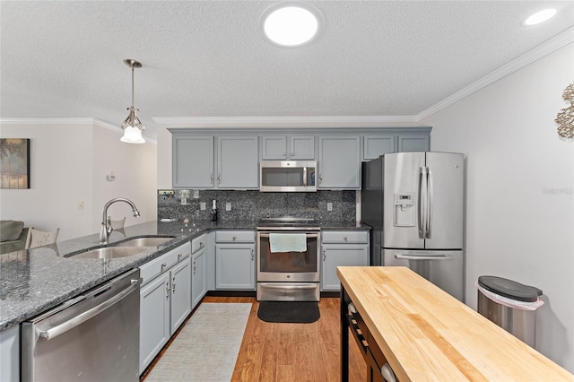 kitchen with appliances with stainless steel finishes, a sink, gray cabinetry, and ornamental molding