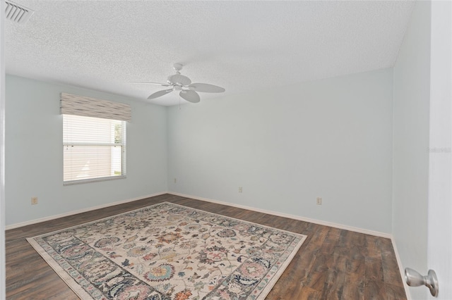 empty room featuring a textured ceiling, visible vents, and dark wood-style flooring