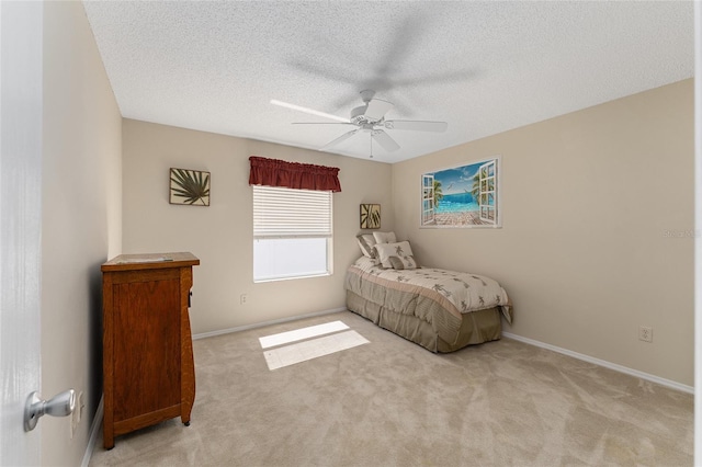 bedroom featuring light colored carpet, ceiling fan, a textured ceiling, and baseboards