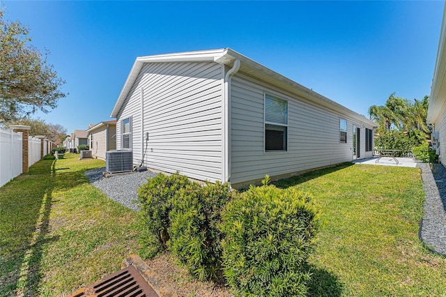 view of home's exterior with a yard, central AC unit, a patio area, and fence