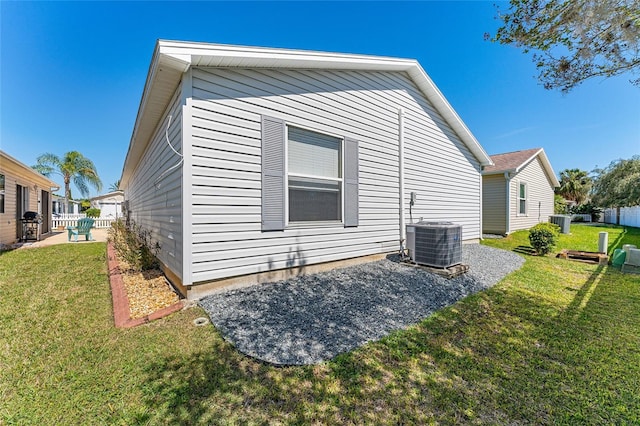 view of side of home with a yard, fence, and central air condition unit