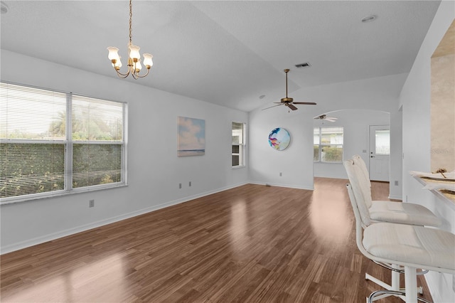 unfurnished living room with lofted ceiling, arched walkways, wood finished floors, visible vents, and baseboards