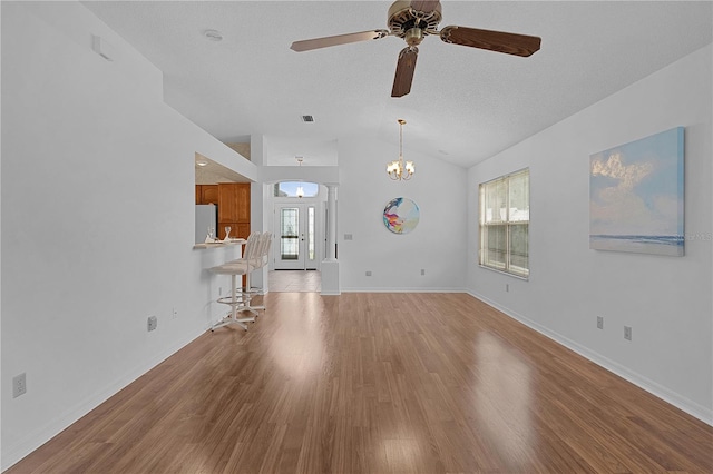 unfurnished living room featuring light wood-type flooring, a wealth of natural light, visible vents, and vaulted ceiling