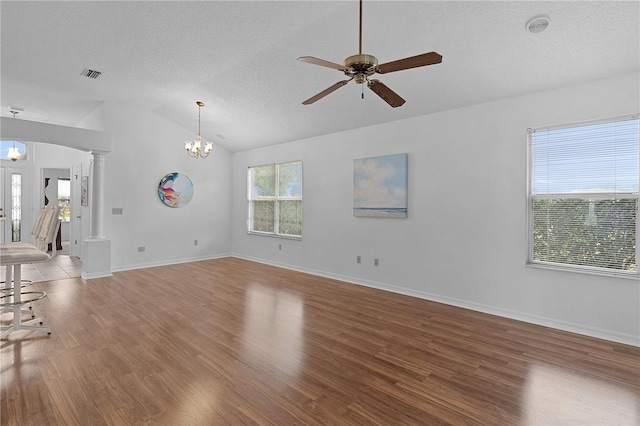 unfurnished living room featuring arched walkways, wood finished floors, visible vents, vaulted ceiling, and ornate columns