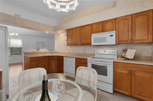 kitchen with white appliances, brown cabinetry, and a sink