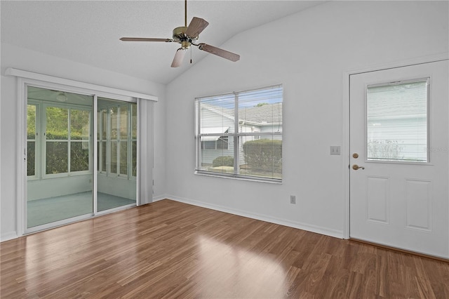 empty room with a healthy amount of sunlight, vaulted ceiling, and wood finished floors