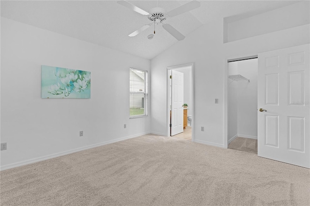 unfurnished bedroom with a closet, light carpet, vaulted ceiling, ensuite bath, and baseboards